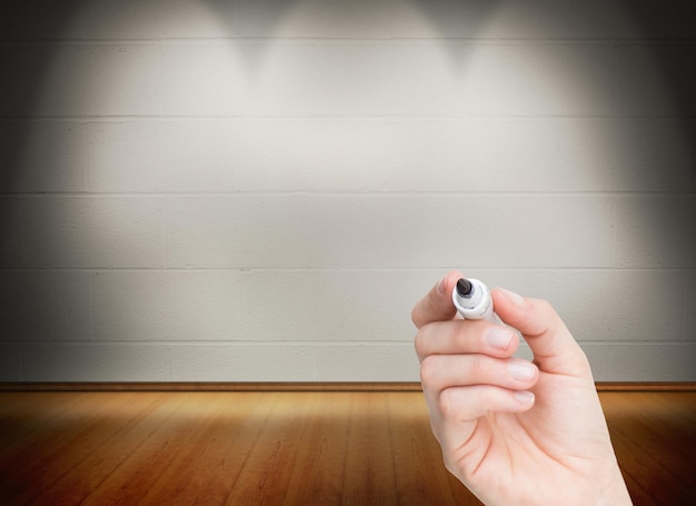 Imagen compuesta de mano femenina sosteniendo un marcador de pizarra negra en una habitación luminosa