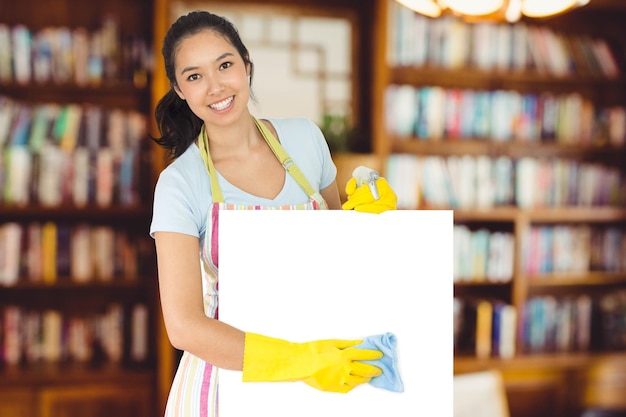 Imagen compuesta de mujer alegre limpiando la superficie blanca