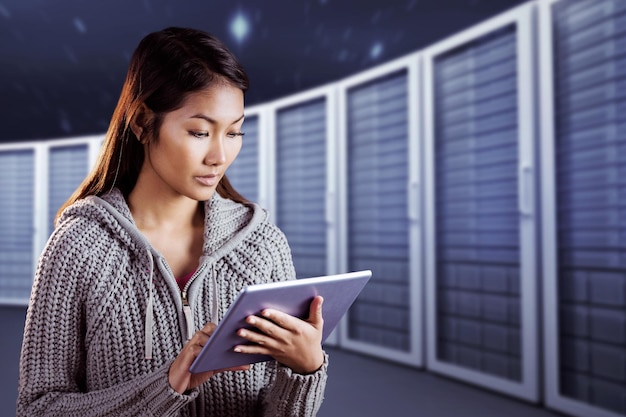 Imagen compuesta de mujer asiática enfocada usando tableta