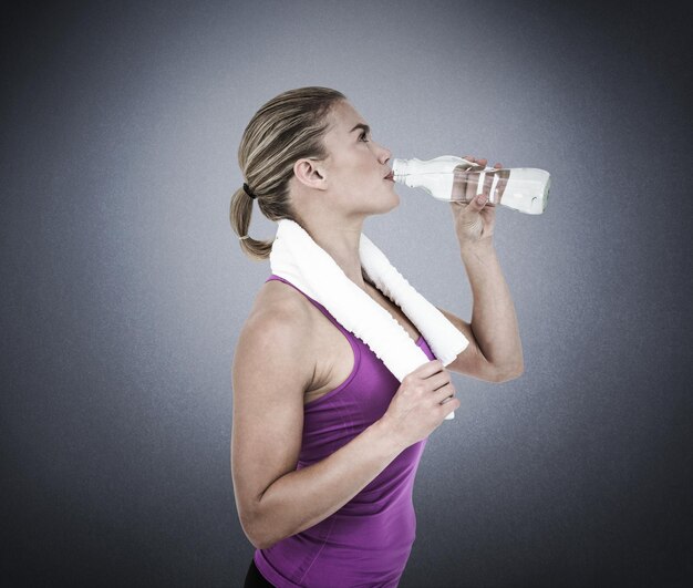 Imagen compuesta de mujer muscular bebiendo agua