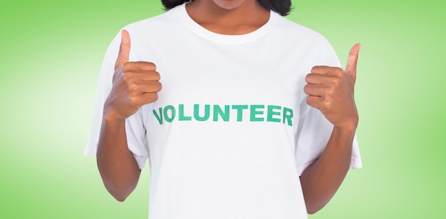 Imagen compuesta de mujer vistiendo camiseta de voluntario y dando Thumbs up