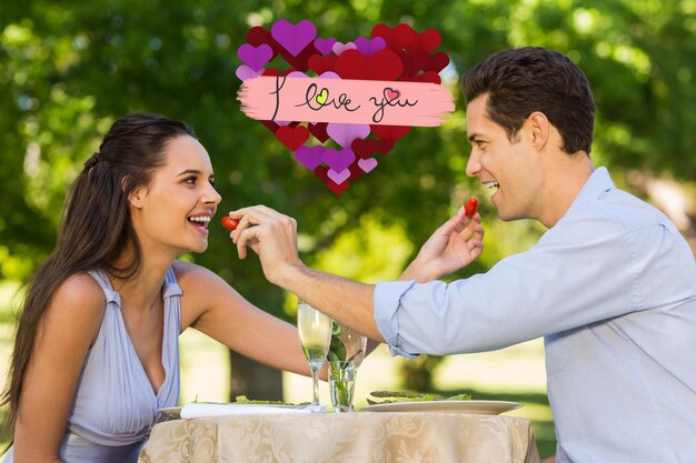 Foto imagen compuesta de un par de fresas de alimentación el uno al otro en la cafetería al aire libre©