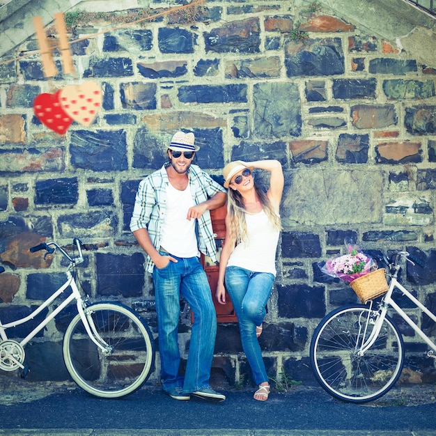 Imagen compuesta de pareja atractiva de pie con bicicletas