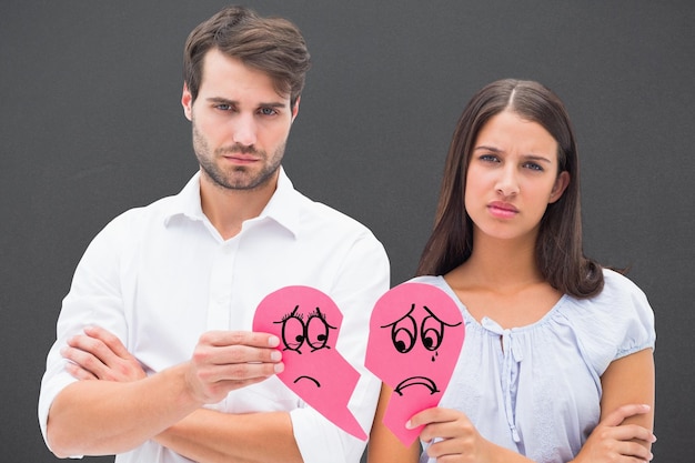 Imagen compuesta de pareja molesta sosteniendo dos mitades de corazón roto