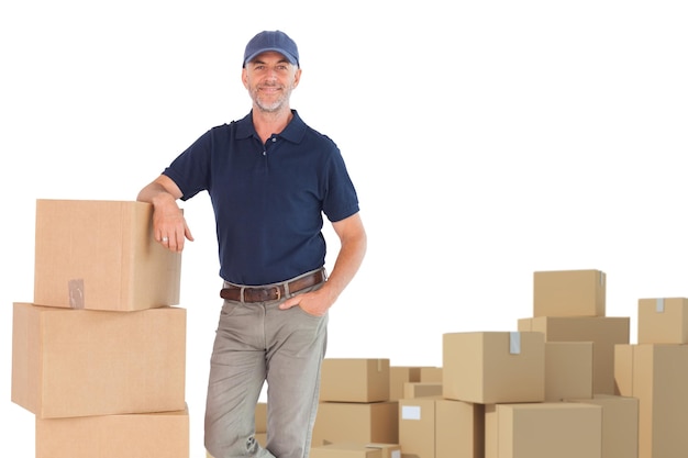 Imagen compuesta de un repartidor feliz apoyado en un montón de cajas de cartón