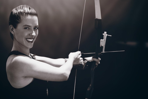 Imagen compuesta de retrato de deportista sonriendo y practicando tiro con arco