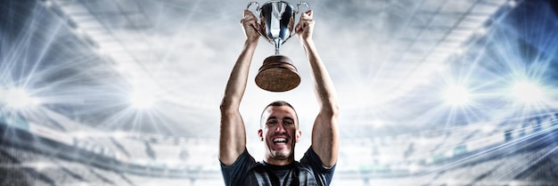 Imagen compuesta de retrato de exitoso jugador de rugby sosteniendo el trofeo