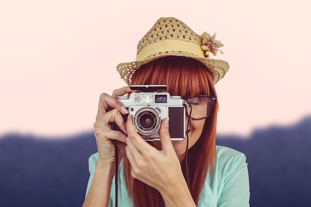 Imagen compuesta de retrato de una mujer hipster sonriente sosteniendo cámara retro