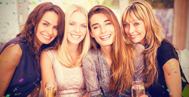 Imagen compuesta de retrato de mujeres hermosas tomando bebidas mientras se sienta en el sofá