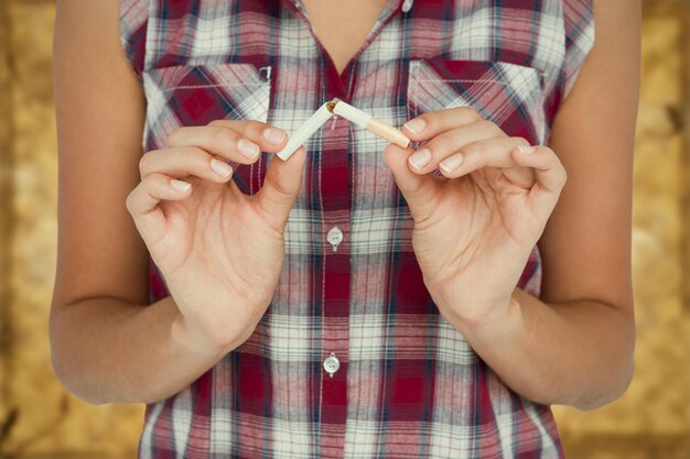 Foto imagen compuesta de la sección media de la mujer chasqueando un cigarrillo