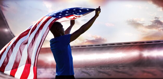 Imagen compuesta de vista trasera del deportista levantando una bandera americana