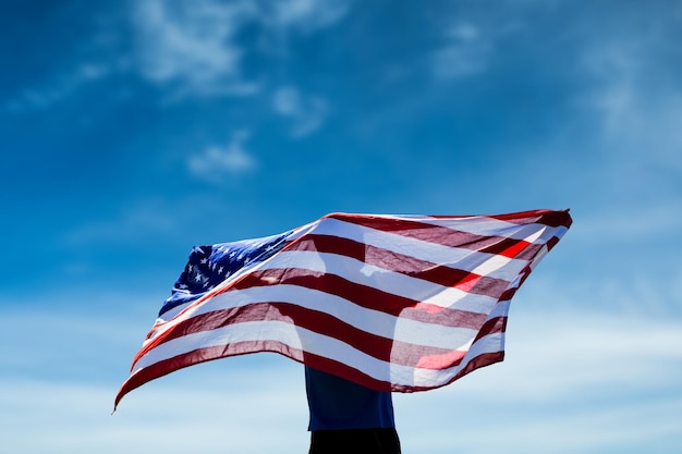 Imagen compuesta de vista trasera del deportista posando con una bandera americana