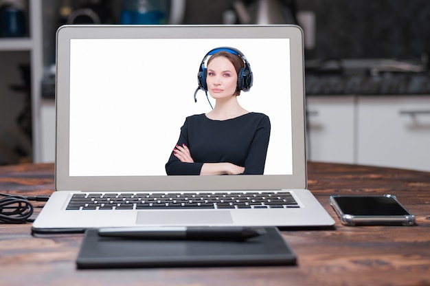 Imagen de una computadora portátil con una pantalla de presentación que muestra a una mujer con auriculares. Concepto de soporte al cliente. Técnica mixta