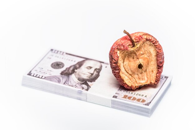 Una imagen conceptual centrada en el dinero de una manzana podrida para varias ideas monetarias