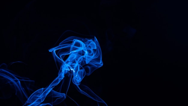 Imagen conceptual de humo de color azul aislado en negro oscuro