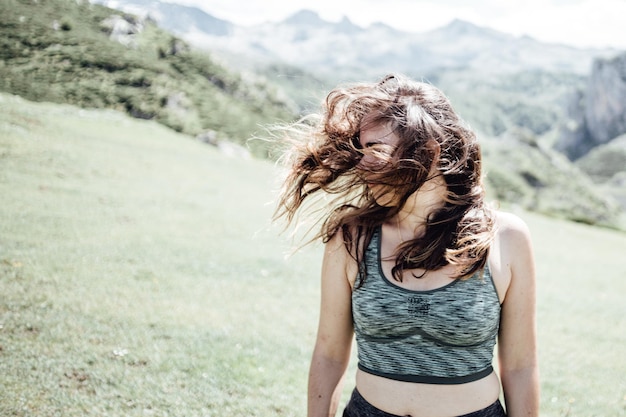 Imagen conceptual de una mujer joven agitando su cabello en la cima de las montañas en ropa deportiva. Copie el espacio del lado izquierdo