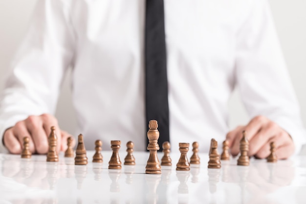 Imagen conceptual de la visión empresarial con un hombre vestido con camisa sentado frente a piezas de ajedrez oscuras