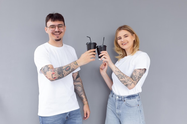 Imagen de contenido pareja hombre y mujer en ropa de mezclilla sonriendo mientras sostiene tazas de café para llevar