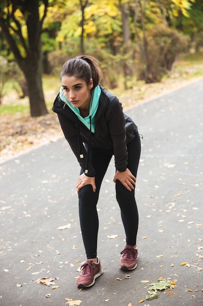 Foto imagen de un corredor de mujer hermosa joven bastante fitness descansar al aire libre en el parque.