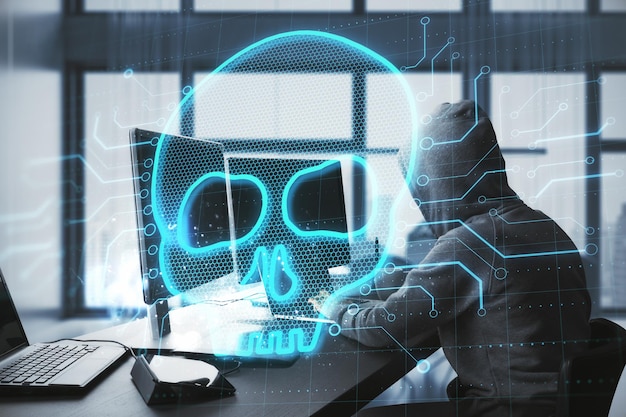 Imagen creativa de hacker en el escritorio usando computadoras con cráneo digital brillante en un fondo borroso Tecnología de hacker y concepto de virus Doble exposición