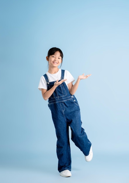 Imagen del cuerpo completo de una chica asiática posando sobre un fondo azul