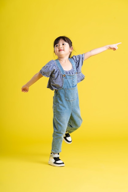 Imagen de cuerpo completo de hermosa niña asiática sobre fondo amarillo