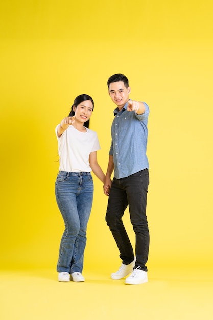 Imagen de cuerpo completo de pareja asiática posando sobre fondo amarillo