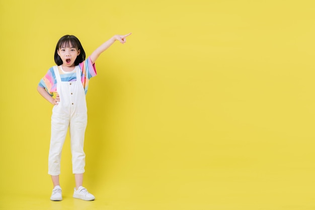 Imagen de cuerpo entero de un niño asiático posando sobre fondo amarillo