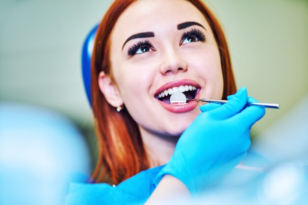 Imagen de dentista con espejo en ángulo mientras examina los dientes del paciente