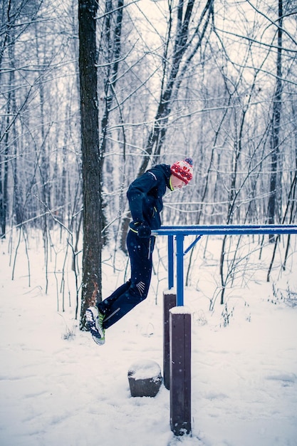 Imagen de deportista en barra horizontal en invierno en el bosque