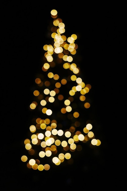 Foto imagen desenfocada de un árbol de navidad iluminado contra un fondo negro