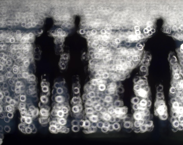 Foto imagen desenfocada de una familia de siluetas disfrutando en el muelle sobre el mar durante el verano