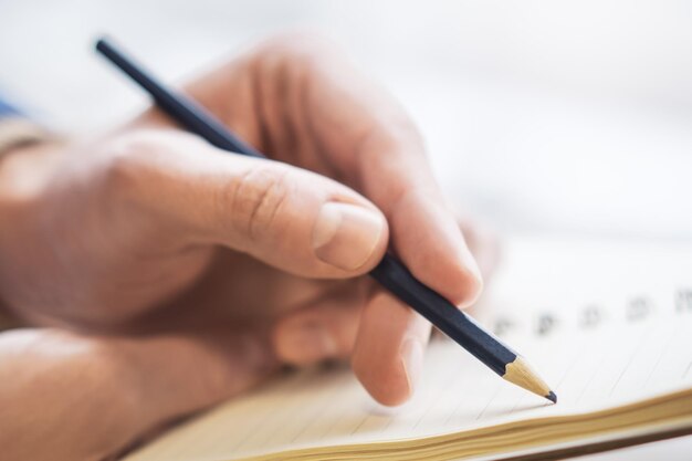 Foto la imagen destaca la escritura a mano de un hombre en un bloc de notas con un entorno ligeramente borroso