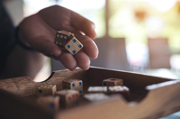 Imagen de detalle de mano sosteniendo y rodando dados de madera