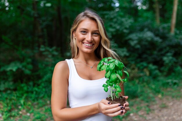 Imagen de detalle de las manos de una mujer sosteniendo plántulas Manos de jardinero femenino sosteniendo un árbol joven en el invernadero