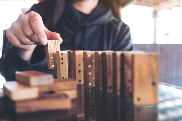 Imagen de detalle de una mujer poniendo juego de dominó de madera en orden en la mesa