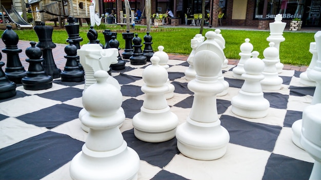 Imagen de detalle de tablero de ajedrez gigante y figuras de ajedrez en el parque. Entretenimiento y diversión para la familia al aire libre