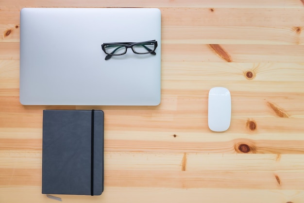 Imagen directamente por encima de la computadora portátil con gafas y diario en la mesa