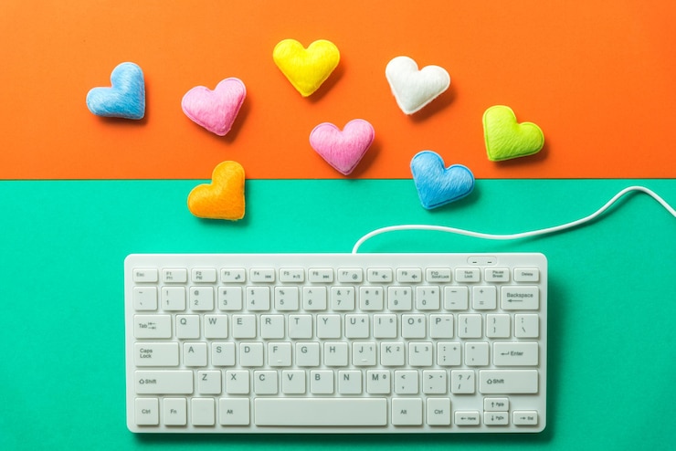 Foto imagen directamente por encima del teclado de la computadora con formas de corazón coloridas sobre un fondo de color