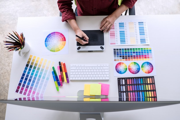 Imagen de un diseñador gráfico creativo trabajando en la selección de colores y dibujando en una tableta gráfica