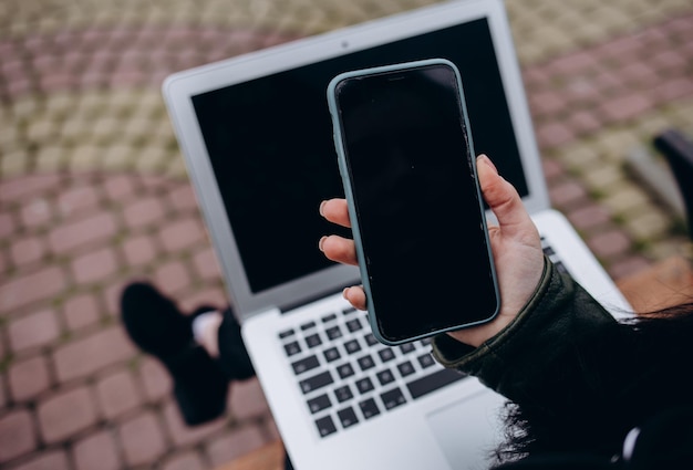 Imagen de diseño de teléfono móvil con pantalla de computadora en blanco con fondo negro para texto publicitario mano humana usando una computadora portátil envía mensajes de texto Diseño de trabajos creativos