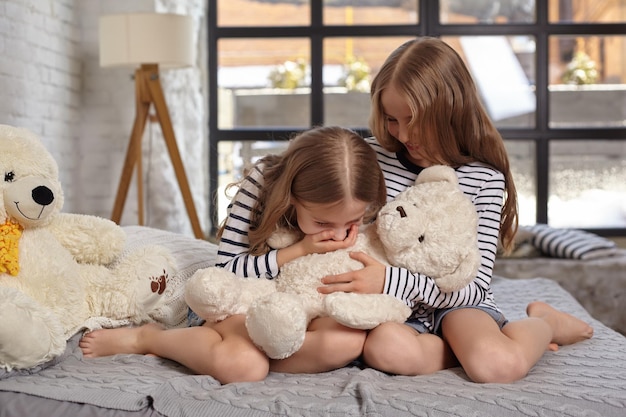 La imagen de dos hermanitas sentadas en la cama de la habitación.