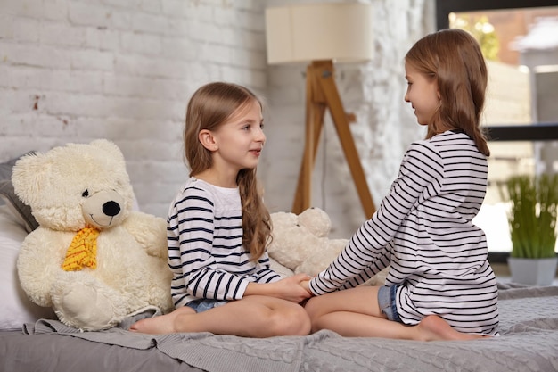 La imagen de dos hermanitas sentadas en la cama de la habitación.