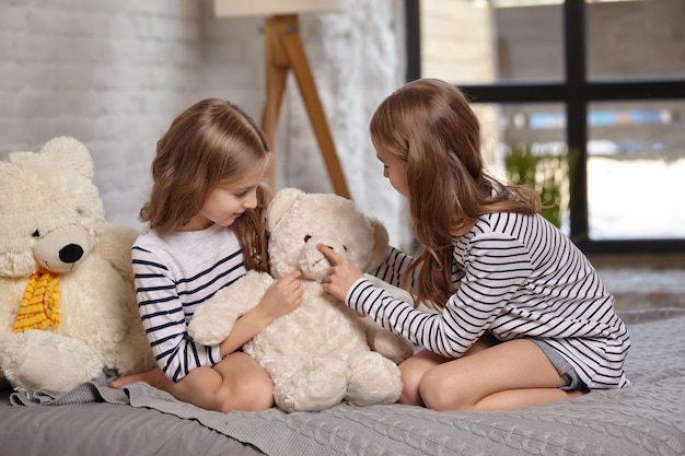 La imagen de dos hermanitas sentadas en la cama de la habitación.