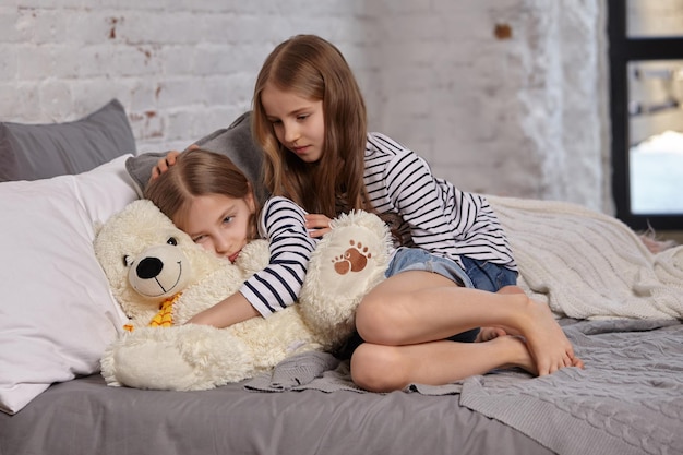 La imagen de dos hermanitas sentadas en la cama de la habitación.