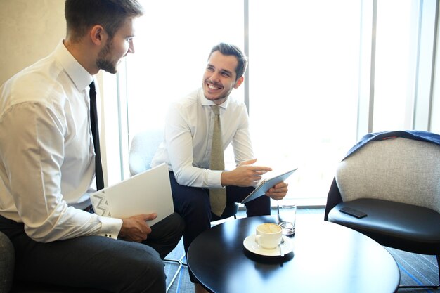 Imagen de dos jóvenes empresarios con touchpad en reunión.