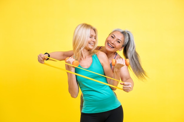 Imagen de dos mujeres con diferente cuerpo, edad y etnia haciendo deporte. Modelos femeninas con ropa deportiva divirtiéndose en el gimnasio. Concepto sobre positividad corporal, autoaceptación y estilo de vida