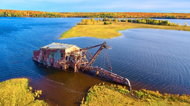 Imagen de una draga hundida en un lago con una isla detrás