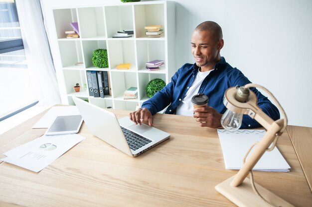 Imagen del empresario afroamericano trabajando en su computadora portátil. Apuesto joven en su escritorio.