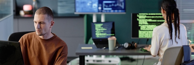 Foto imagen de encabezado de un programador masculino codificando en una computadora trabajando con colegas en la oficina